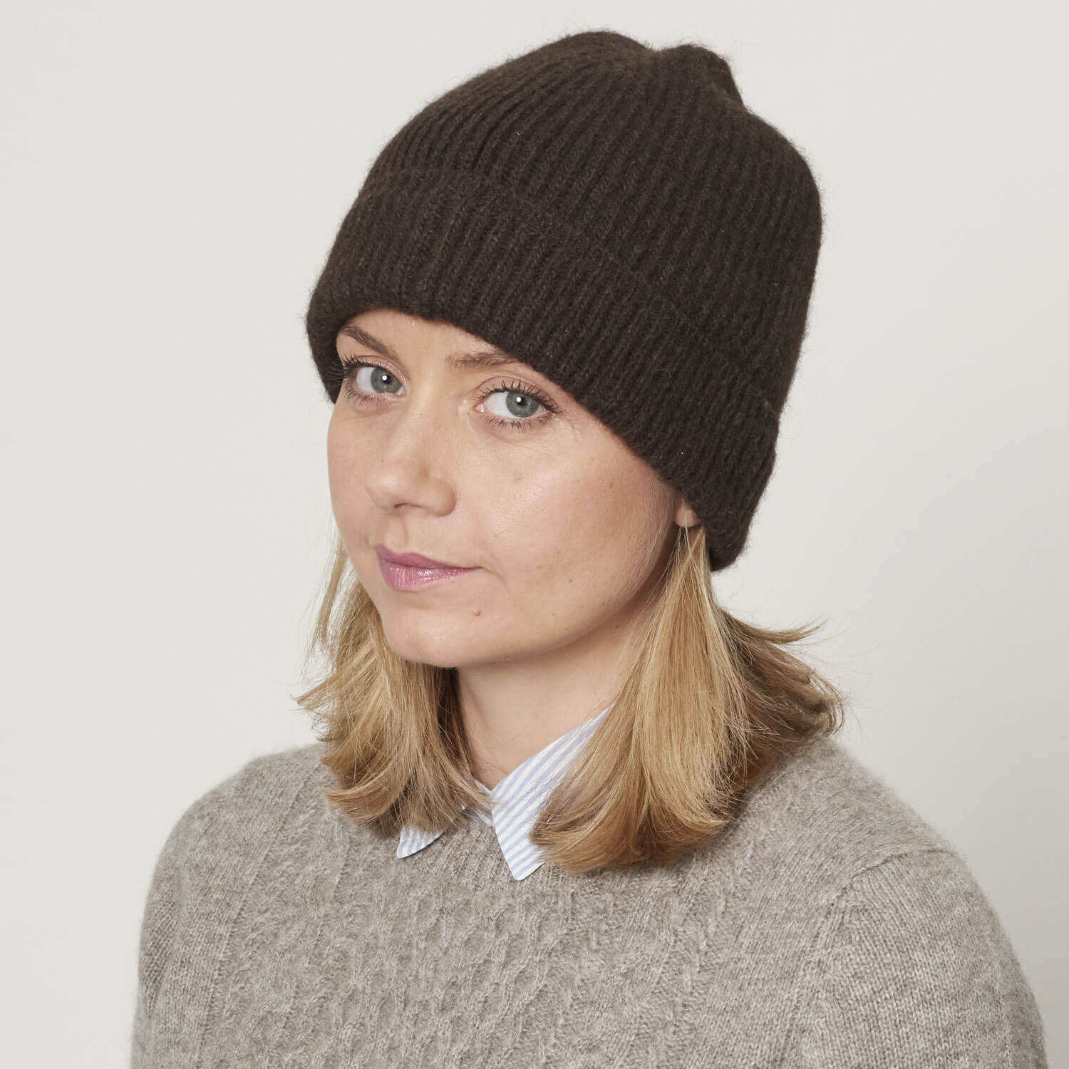Model med strikket yakuld hue i mørk brun naturfarve. 