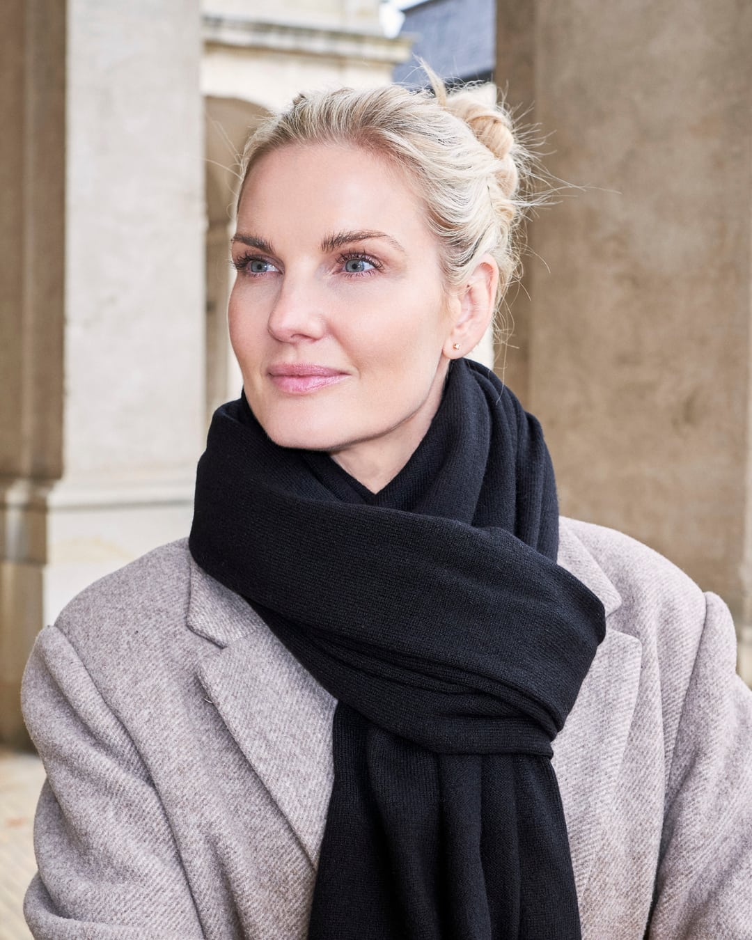 Model med det store tætstrikkede cashmere tørklæde i Black, bundet løst om halsen.