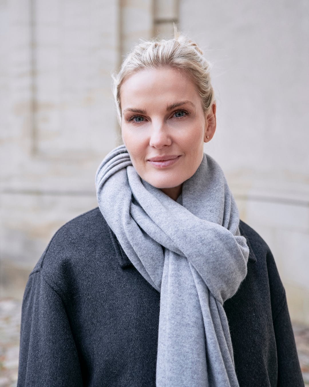 Model med det store tætstrikkede cashmere tørklæde i Light grey, draperet løst om halsen.