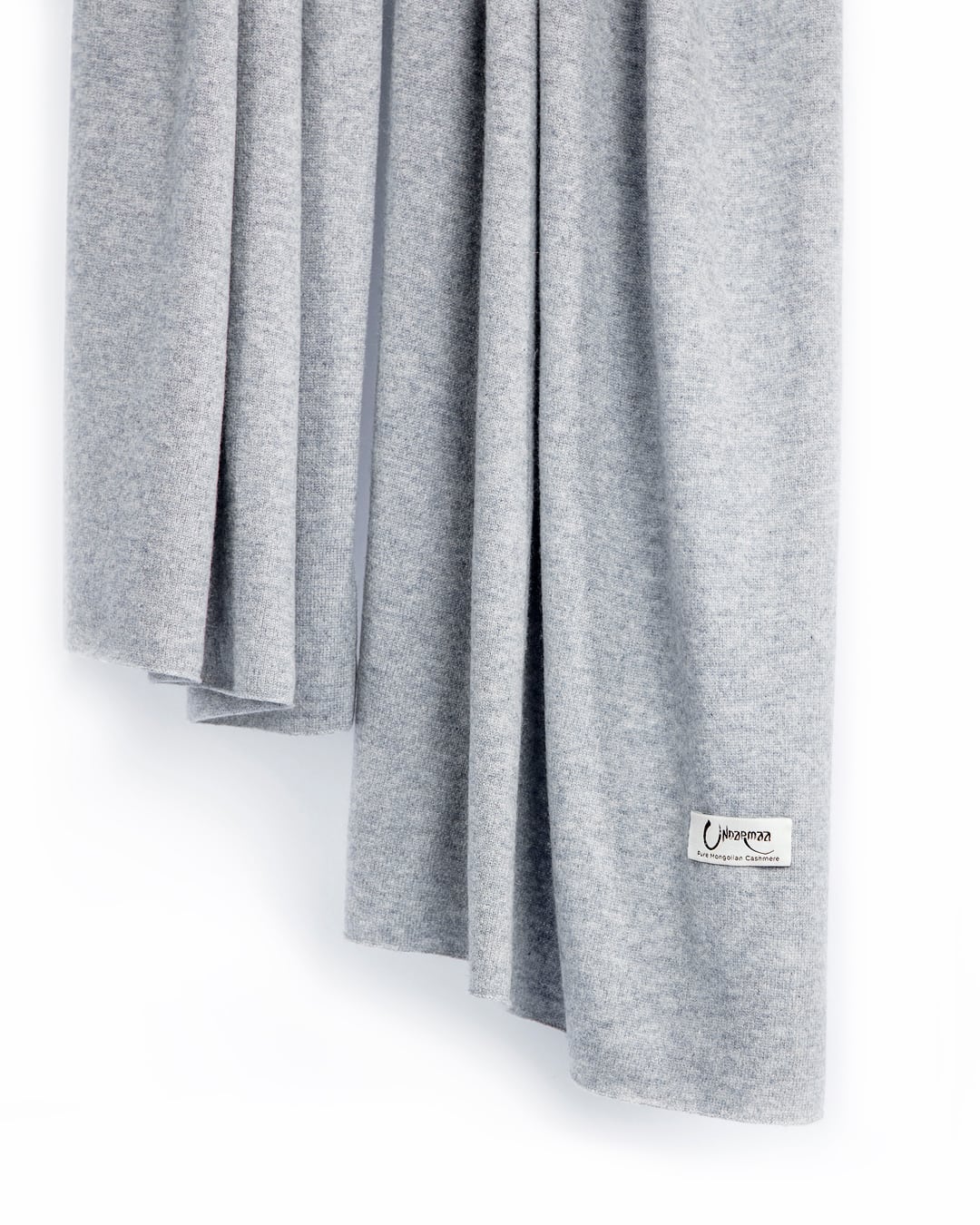 Det store tætstrikkede cashmere tørklæde i Light grey hænger løst.