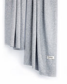 Det store tætstrikkede cashmere tørklæde i Light grey hænger løst.
