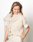 Model med det store naturfarvede cashmere tørklæde i lys gråbeige svøbt om halsen.