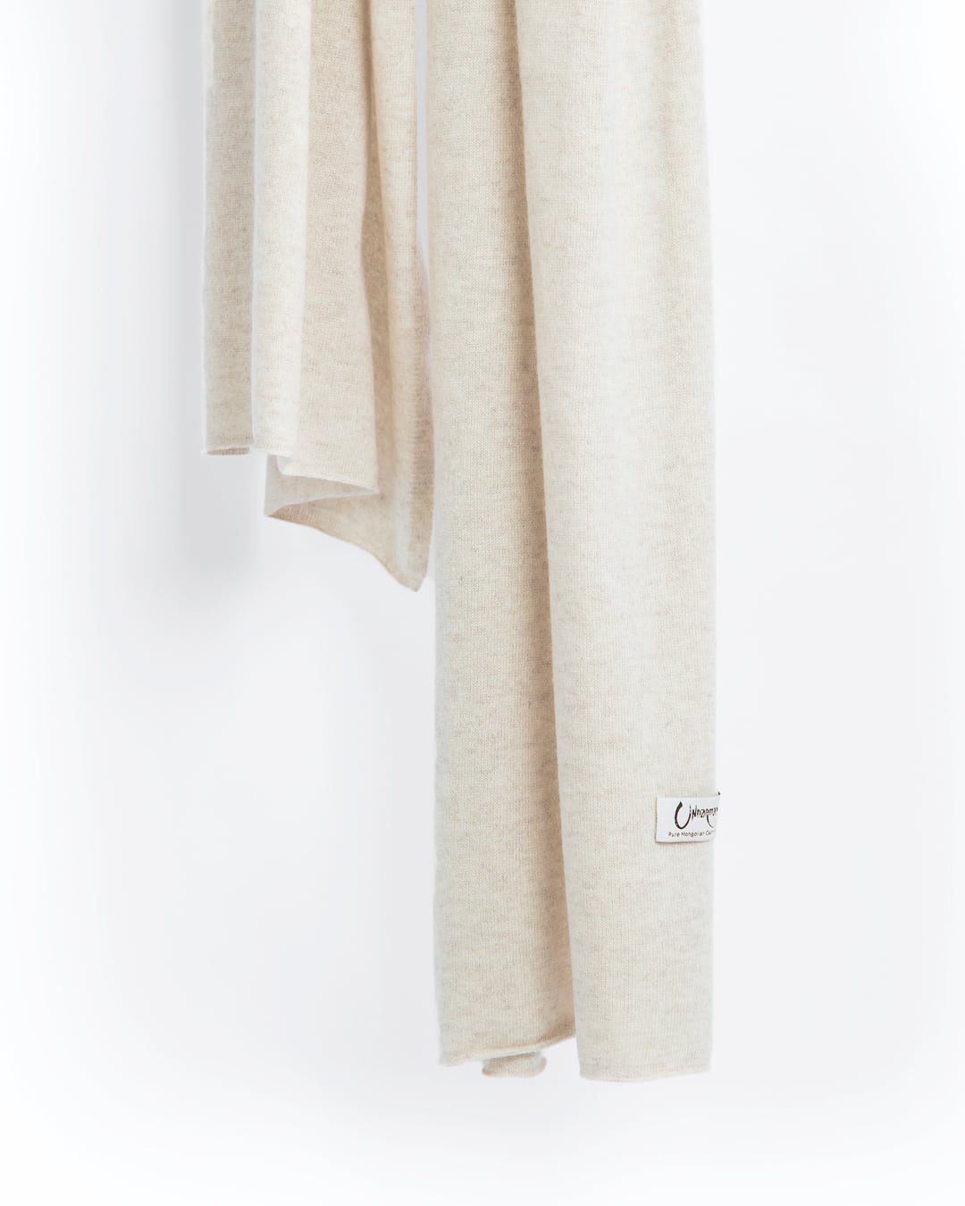 Det store cashmere tørklæde, her i naturfarvet lys gråbeige hænger løst ned.