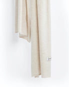 Det store cashmere tørklæde, her i naturfarvet lys gråbeige hænger løst ned.