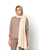 Model med det store naturfarvede cashmere tørklæde i lys beige svøbt om halsen.