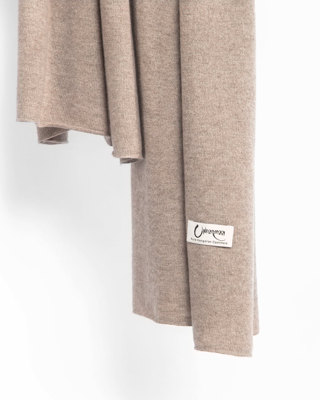 Det store cashmere tørklæde, her i naturfarvet mørk gråbeige hænger løst ned.