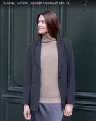 Kvinde iført Zaya turtleneck i Natural taupe cashmere under blazer, udendørs.