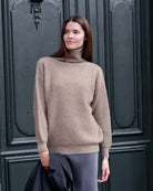 Kvinde iført Zaya turtleneck i Natural taupe cashmere, afslappet positur.