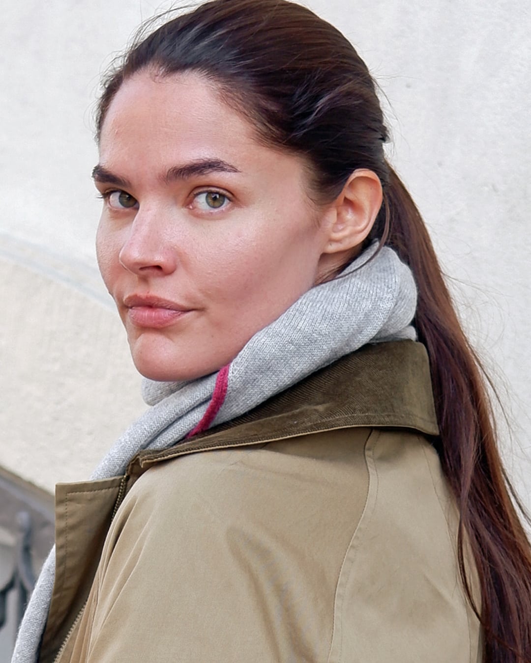 Zul trekantet tørklæde i lysegrå, set bagfra over en trenchcoat.