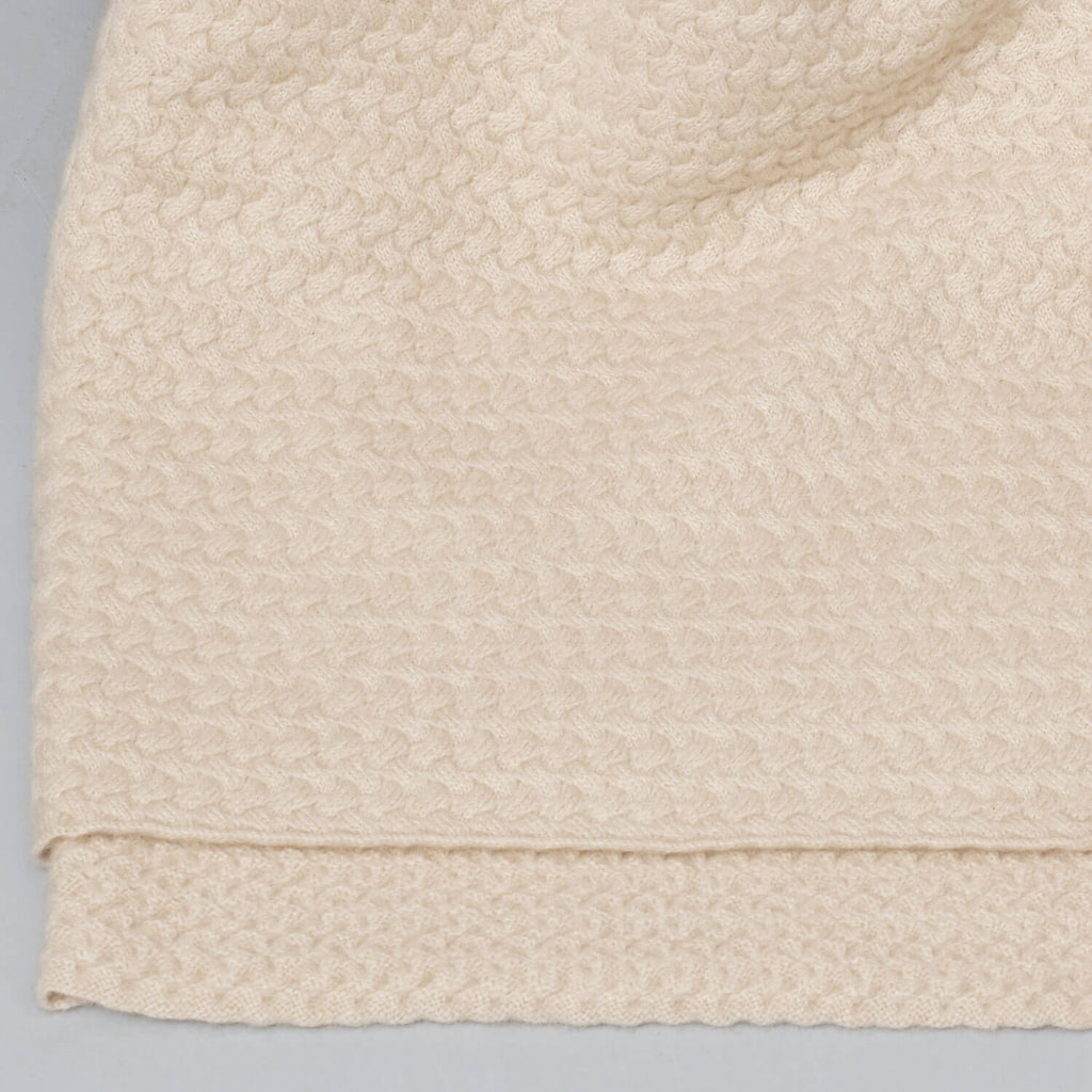 Detalje af den fine tekstur på cashmere plaiden i en elegant lys beige farve.