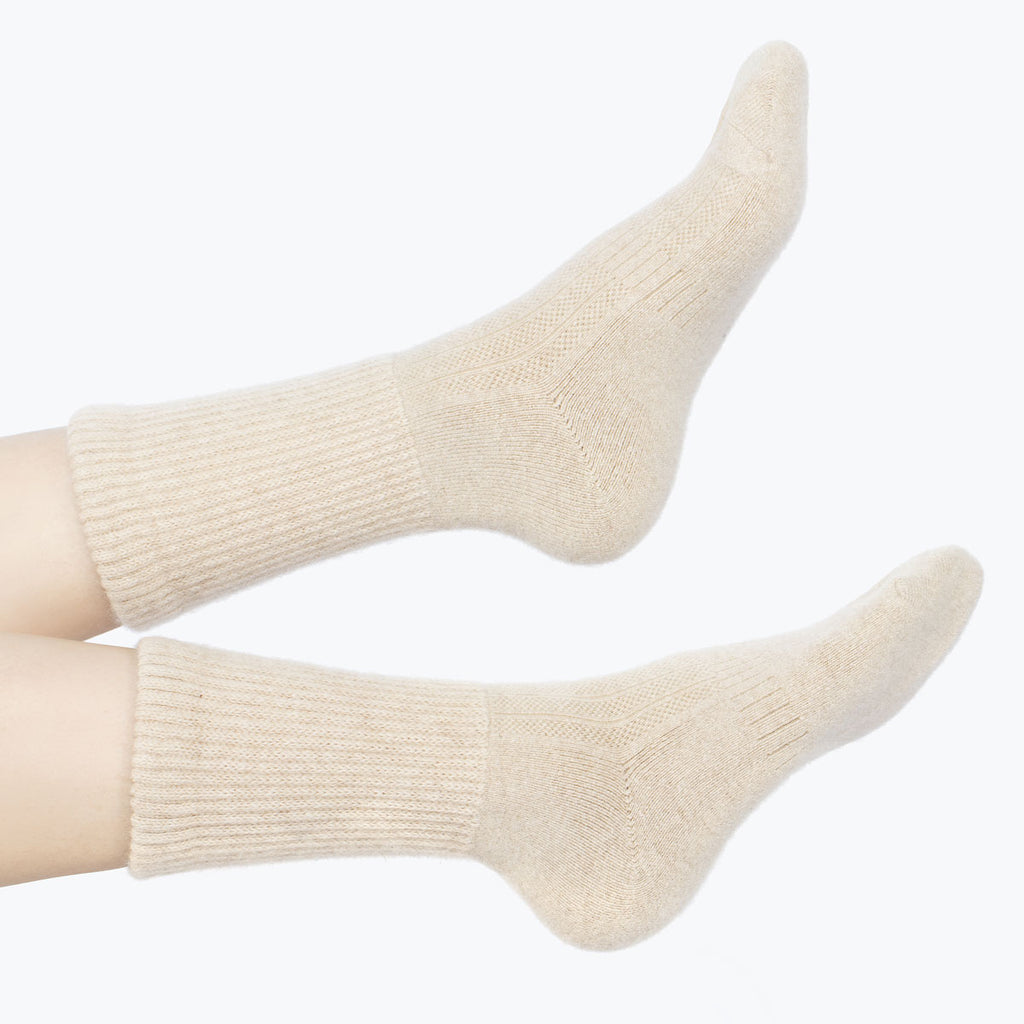 Model iført lys beige cashmere sokker fra Undarmaa, afslappet i et hyggeligt miljø.