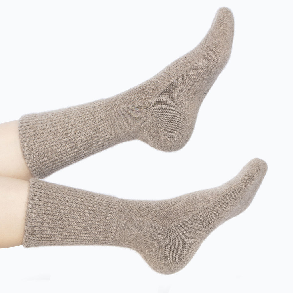 Model iført mørk gråbeige cashmere sokker fra Undarmaa, afslappet i et hyggeligt miljø.