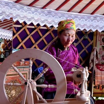 Kvinde i en ger i Mongoliet, der spinder yakuld garn på en rok