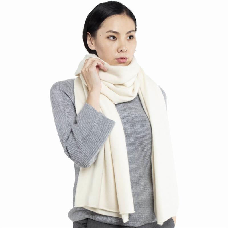 Model med det store naturfarvede cashmere tørklæde i hvid svøbt om halsen.