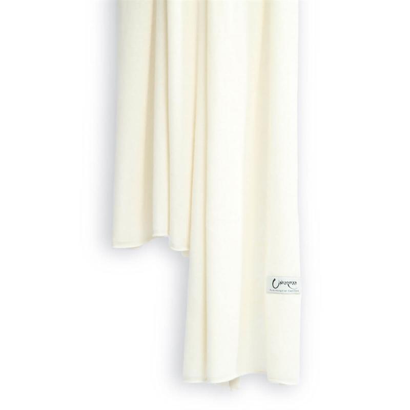 Det store cashmere tørklæde, her i naturfarvet hvid hænger løst ned.