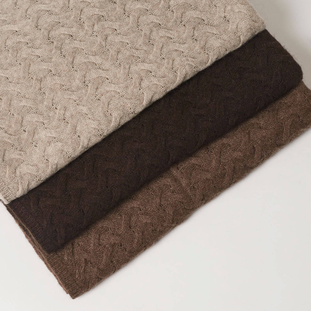 Nærbillede af det detaljerede mønster og de naturlige farvevariationer som det mønsterstrikkede yakuld tørklæde findes i, platingrå, mørk brun og brun. 